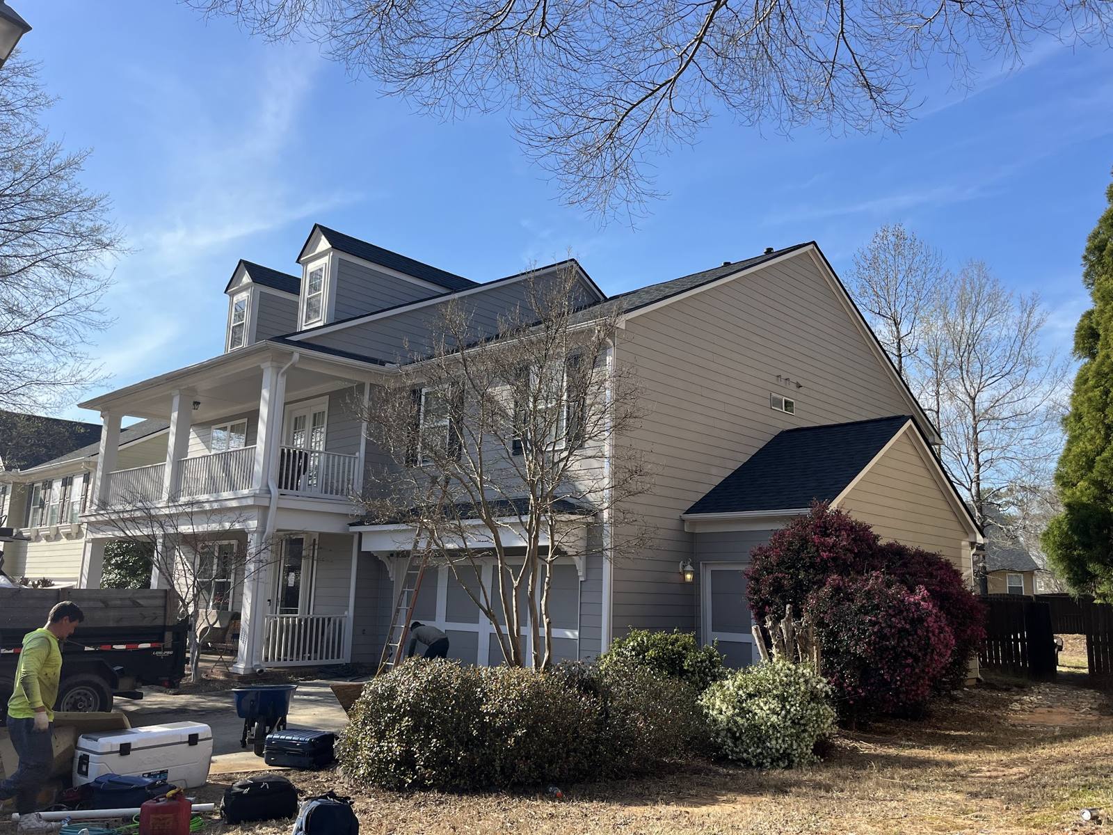 Extra Roofing crew and equipment outside a two-story home during a roof replacement