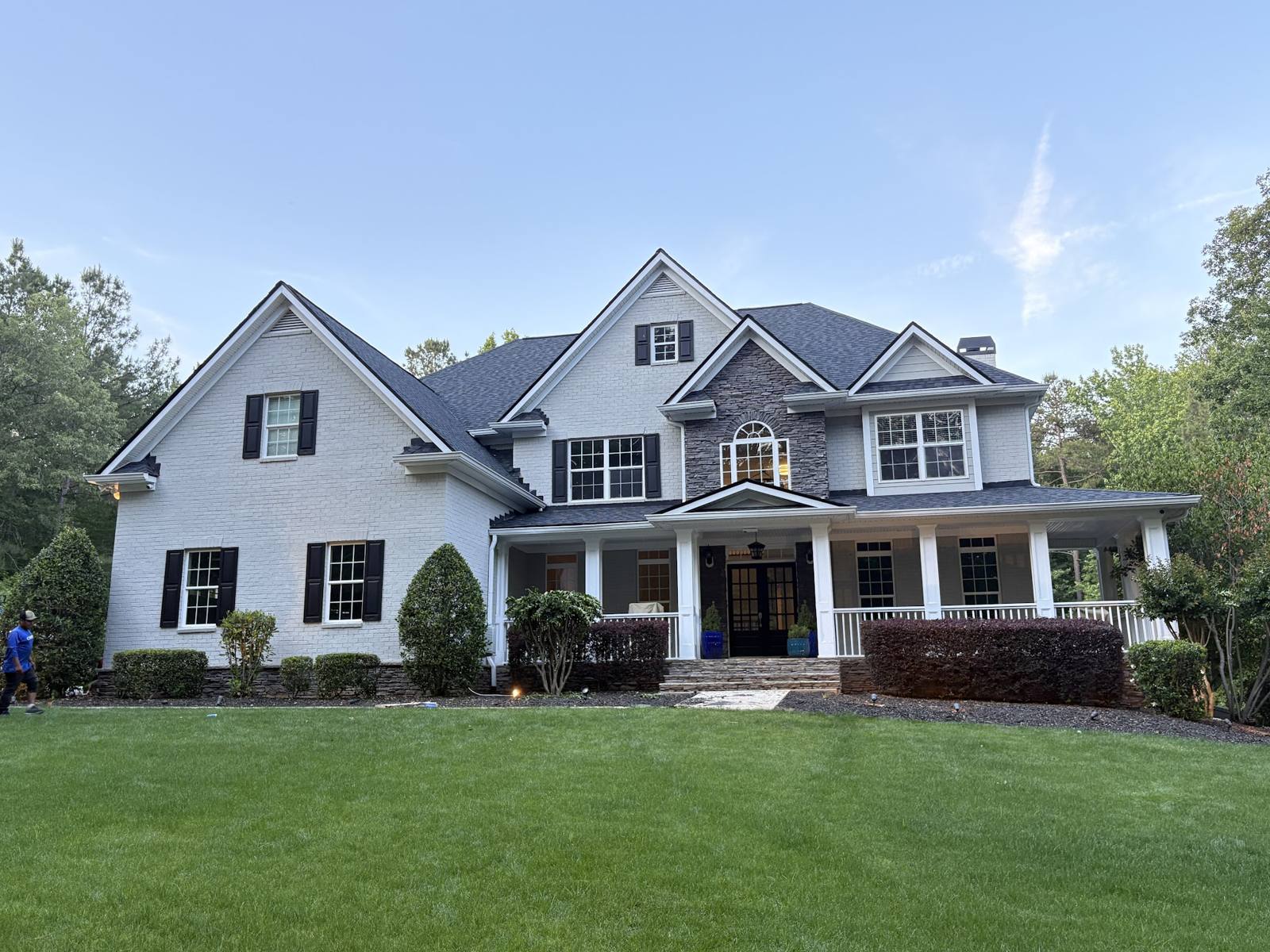 Large white brick house with a new charcoal shingle roof, finished by Extra Roofing
