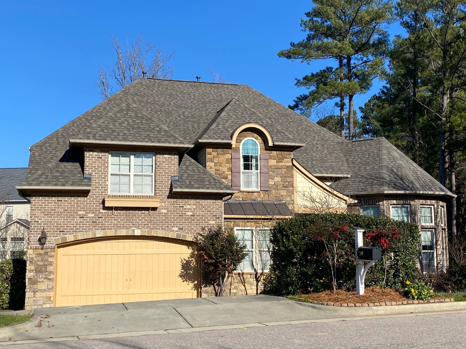 Brick and stone home with a new roof over the garage