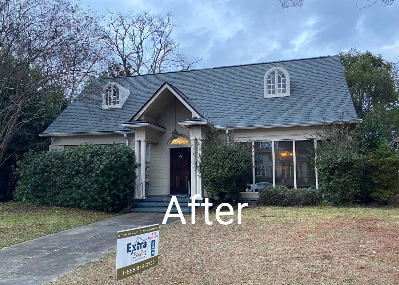 After: the same house with a new grey shingle roof and an Extra Roofing sign